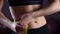 Female flat belly closeup, woman using measuring tape to show weightloss result