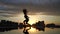 Female flexible dancer jumping in slow motion during sunset on cityscape background with reflection in the water