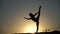 Female flexible dancer showing her flexibility by showing her split in slow motion during sunset on. Concept of freedom