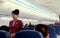 A female flight attendant walks on the aisle to check passengers