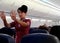 A female flight attendants show passengers about safety instruction on board with hand signal