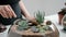 Female florist gardener decorates a mini garden in a glass vase with succulents and cacti in the sand.