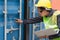 Female foreman checking the number on containers box door with a laptop from Cargo freight ship at Cargo container shipping