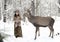 Female forest dweller with a wild horned deer in the winter forest
