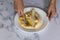 Female with a fork crushes bananas in a white plate making banana bread in the kitchen