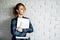 Female freelancer with laptop in her hands standing against white brick wall.