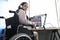 Female freelancer programmer or streamer in modern headphones sits in wheelchair and uses computer