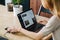 Female freelancer working at the dining table, reaching for a phone on a pad