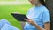 Female freelancer working on tablet pc, sitting on grass in park, remote access