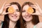 Female friends keeping fresh oranges and posing in studio