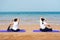 Female friends practicing yoga on the beach