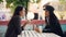 Female friends are sharing news talking sitting at table in open-air cafe on warm autumn day and drinking cocktails