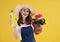 Female gardener holding fertilizer and flower pot with pelargonium