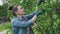 Female gardener with secateurs shearing lilac bush after flowering