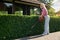 Female gardener shaping bushes with electric trimmer