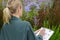 Female gardener writing on clipboard by flowers