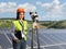 Female geodetic surveyor on a photovoltaic solar panel farm