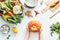 Female girls hands holding pumpkin on white table background with various organic farm vegetables und pot, top view. Seasonal