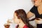 Female with glasses dyeing woman hair in red color with brush in hands in white latex gloves on white background. Hair