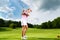 Female golf player on course doing golf swing