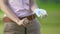 Female golf player holding ball and club waiting for opponent on golf course