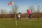 Female Golfer chipping Golf Ball on Cup with Flag