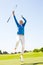 Female golfer leaping and cheering