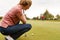 Female Golfer Lining Up Shot On Putting Green As Man Tends Flag