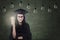 Female graduate holding lit bulb under lamps