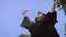 Female graduate throwing graduation cap in the air