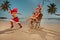 Female group wearing red bikini ride in rocking chair Santa Claus, having fun on the beach. Ð¡hristmas vacation concept of