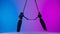 Female gymnastic duet isolated on neon studio background. Girls aerial dancers performers spin on acrobatic trapeze with