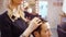 Female hairdresser cutting hair of man client at beauty parlour