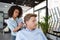 Female hairdresser cutting hair man client at beauty parlour
