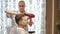 Female hairdresser doing hairstyle to businessman in salon.