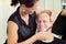 Female hairdresser shaving beard of man