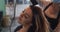 Female hairdresser wearing face mask blow drying hair of female customer at hair salon