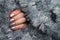 Female hand with beautiful holiday manicure - silver glittered nails on Christmas tinsel background with copy space