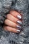 Female hand with beautiful holiday manicure - silver glittered nails on Christmas tinsel background. Vertical banner for