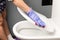 Female hand in a blue glove wipes a white toilet bowl with a rag