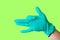 Female hand in blue latex glove makes a gesture resembling a dog with open mouth isolate malachite background. Medical health