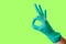 Female hand in blue latex glove makes a gesture resembling a dog with open mouth isolate malachite background. Medical health