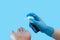 Female hand in a blue medical glove sprays an antiseptic in a female hand on a blue background. The concept of protection against