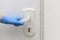 A female hand in a blue protective glove holds a doorknob and is about to open the door. Antibacterial prophylaxis in times of