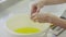 Female hand breaks egg and separate the yolk from the protein to make a cream