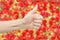 Female hand on bright red fresh blurred strawberry background. The thumb up. Crop quality concept. Symbols and gestures.
