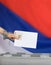 Female hand casts ballot paper in the ballot box.