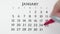 Female hand circle day in calendar date with a red marker. Business Basics Wall Calendar Planner and Organizer. JANUARY