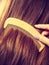 Female hand combing hair with wooden comb