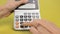 A female hand is doing some calculations on a calculator close-up on a yellow background